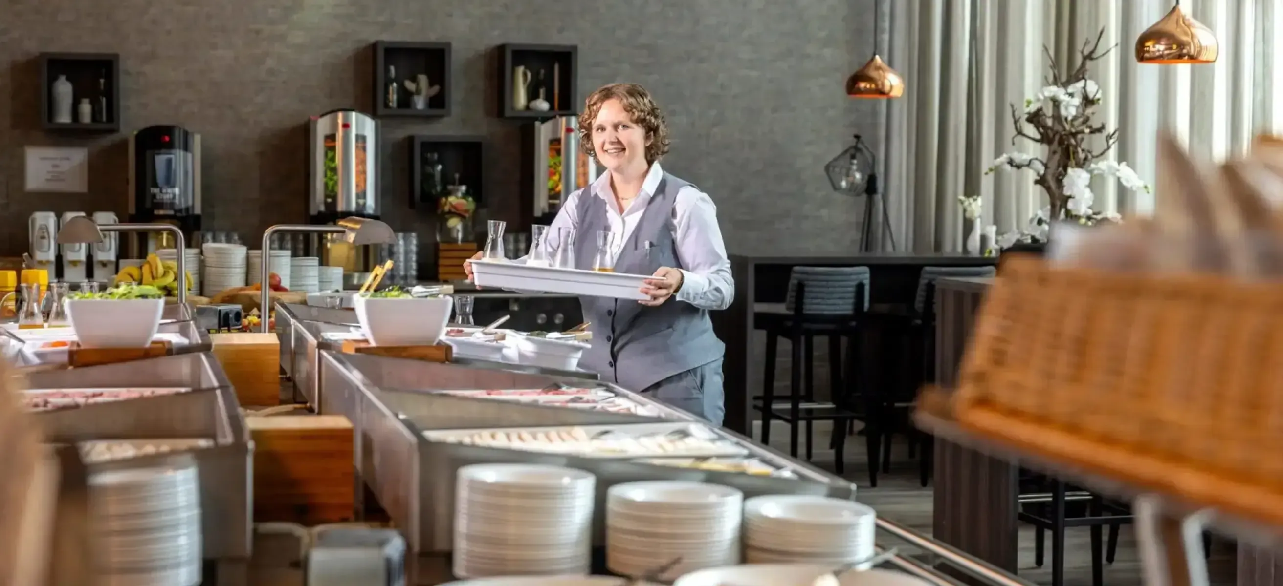 Foto van medewerker Business Center Netherlands (BCN) die de catering in de kantine klaarzet.