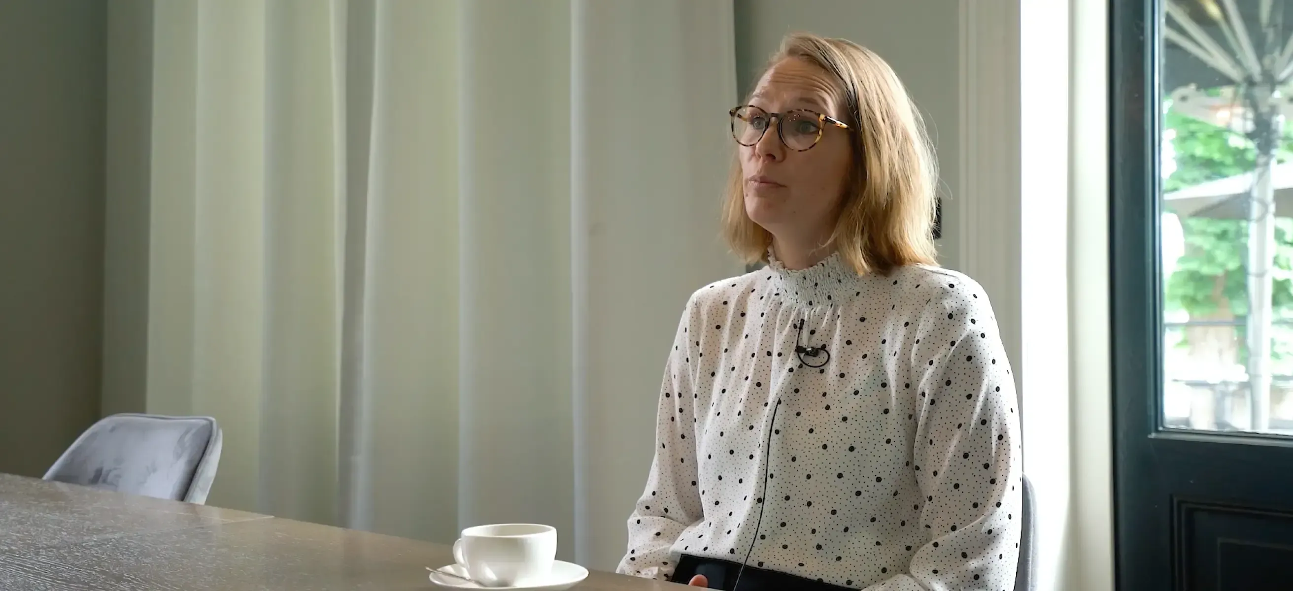 a woman sitting at a table with coffee being interviewed about the VenueSuite booking engine