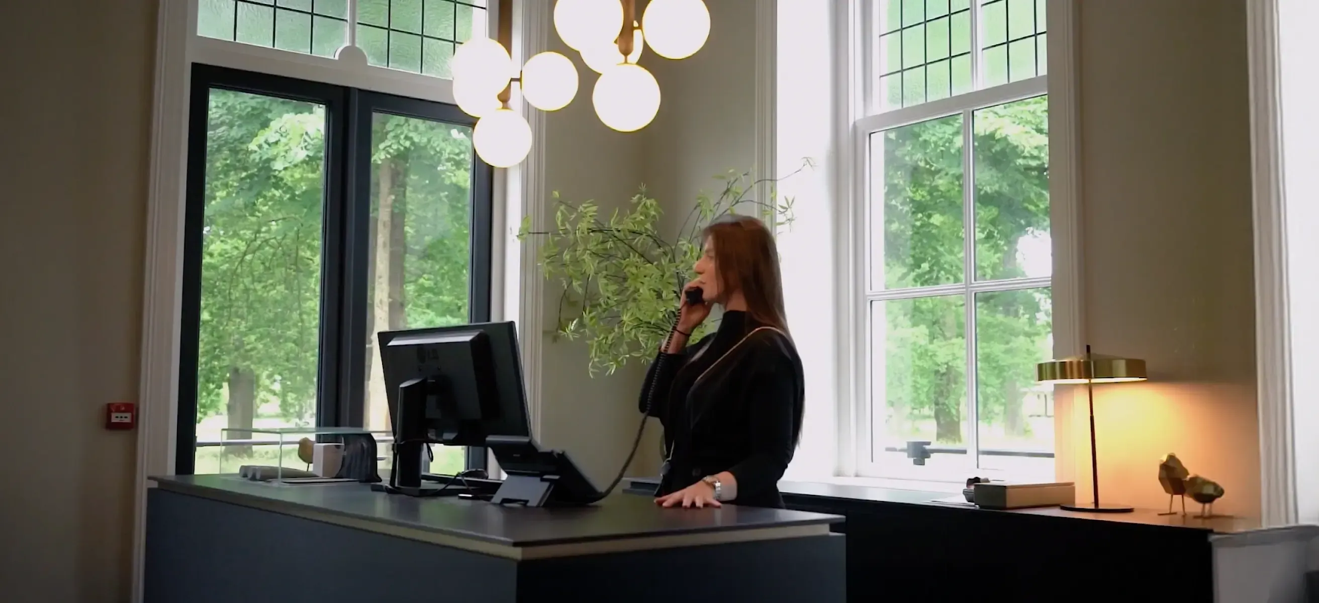 the front desk of Pillows Hotels with a woman providing customer service on the phone.