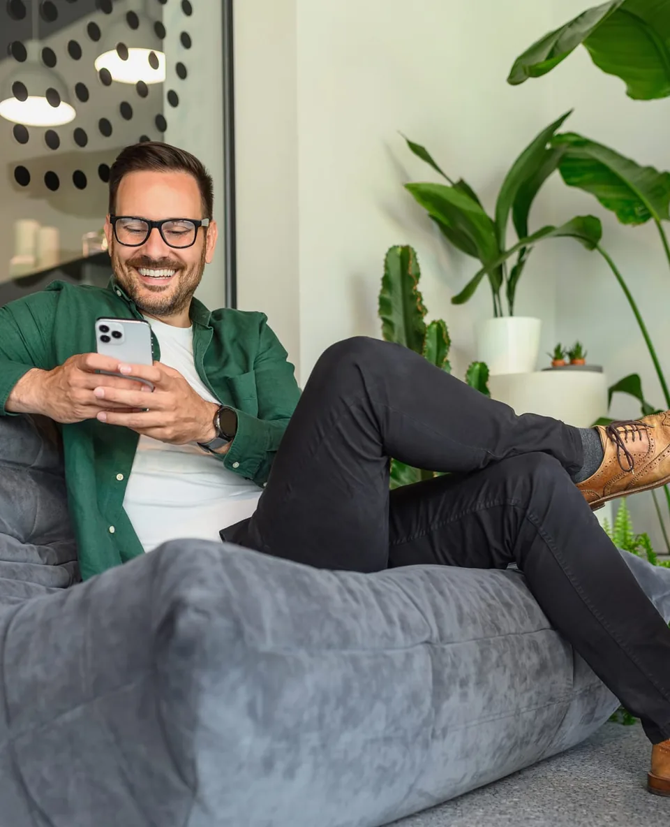 Man on a sofa smiling while using VenueSuite on his phone